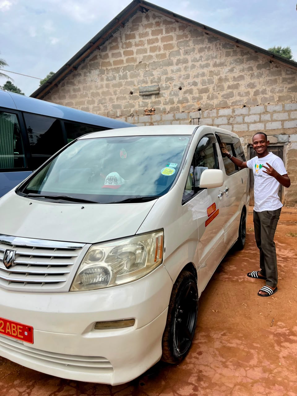 Papi standing next to his white tour van in Zanzibar